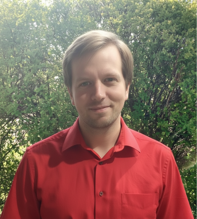 Teilhabeberater: Felix Reischmann Der Berater Felix Reischmann steht, schaut freundlich und hat ein rotes Hemd an