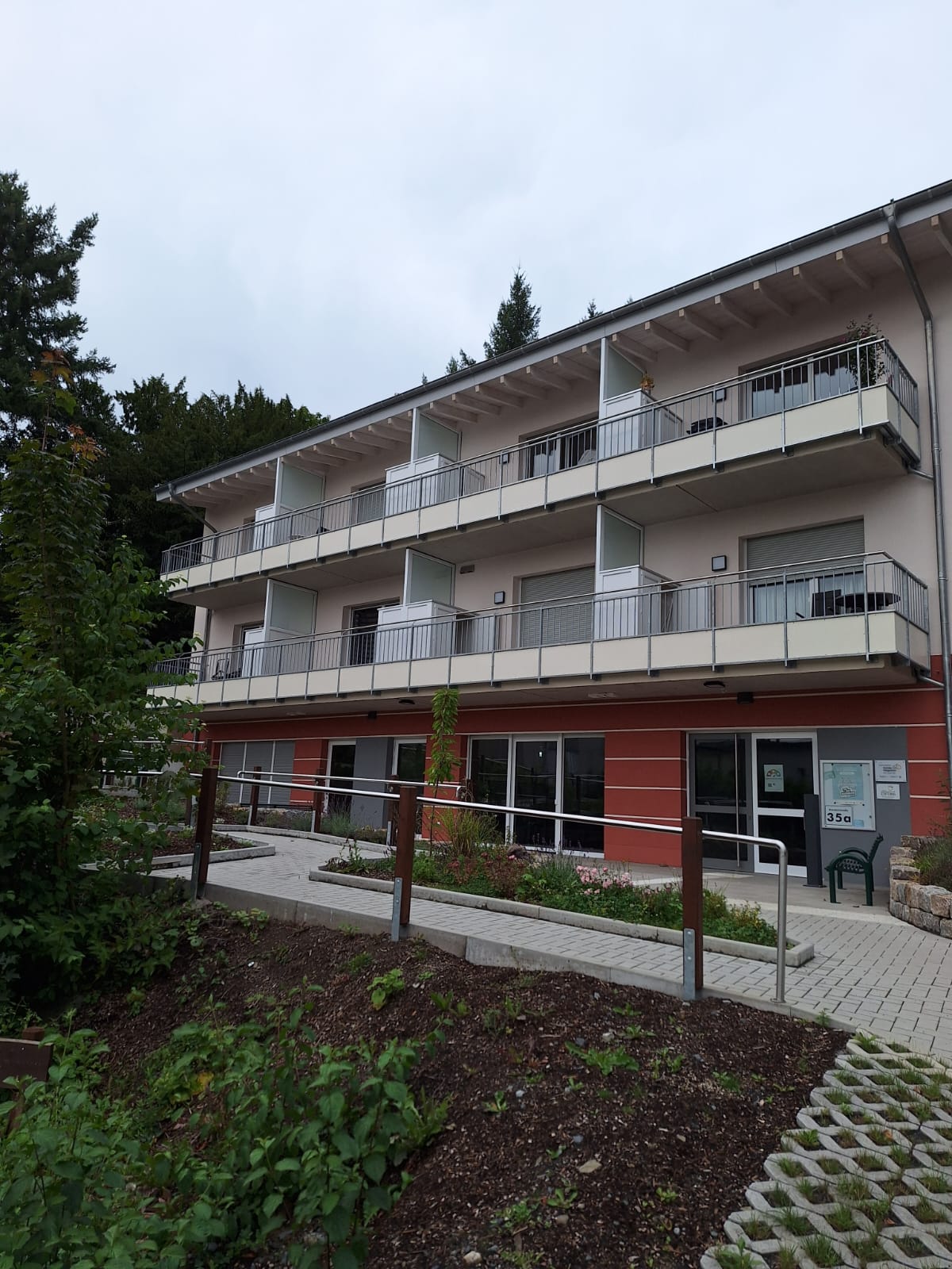 Die Südseite des Hauses mit dem Nachbarschaftstreffs, dem Eingang dazu im Gartengeschoss, darüber 2 mal je vier Balkone der Apartments