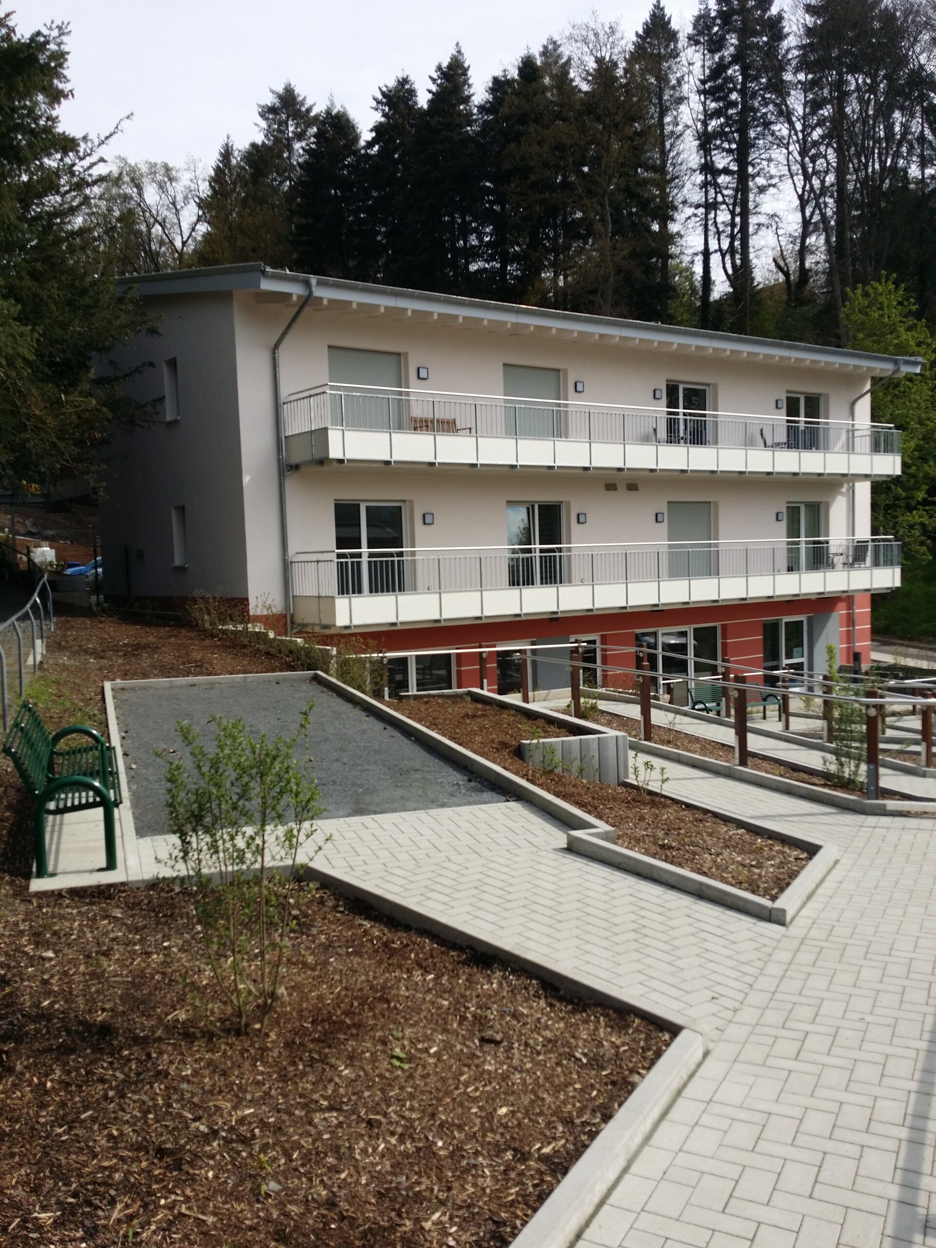 Die Südseite des Hauses mit dem Nachbarschaftstreffs, dem Eingang dazu im Gartengeschoss, darüber 2 mal je vier Balkone der Apartments